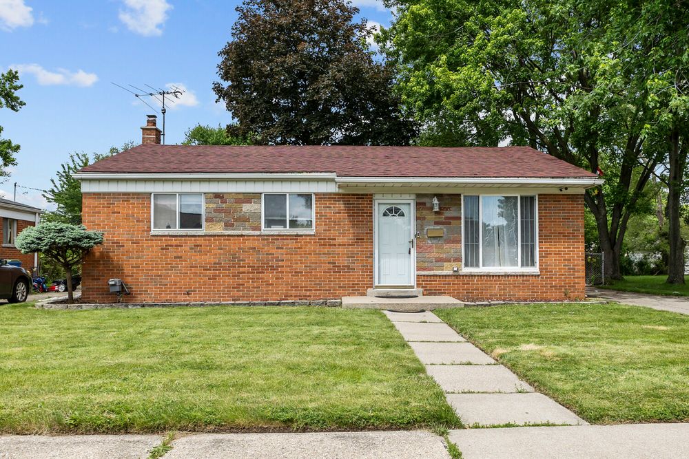 Classic brick ranch home with white front door, manicured lawn, mature trees, and chimney.