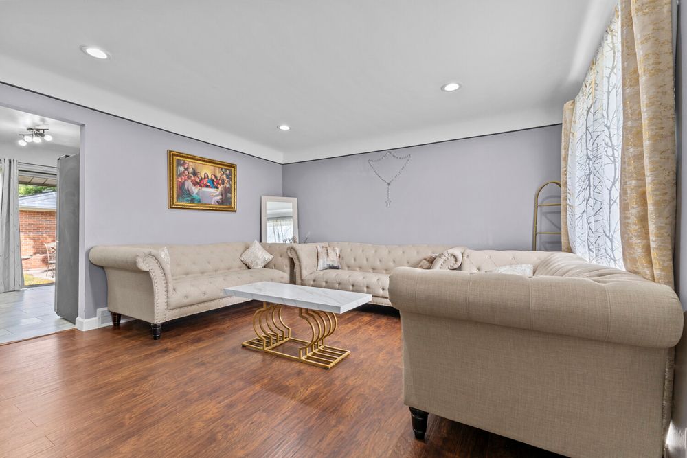 Bright living room with beige tufted sofas, hardwood floors, recessed lighting, and crown molding.