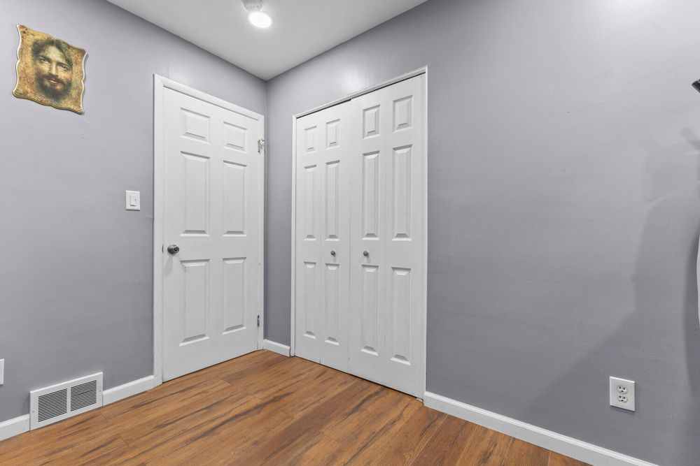 Simple room with hardwood floors, gray walls, and white six-panel closet doors.