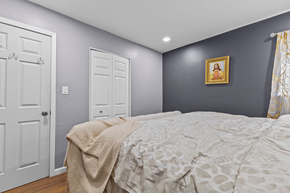 Bedroom with gray walls, white closet doors, hardwood floors, and recessed lighting.