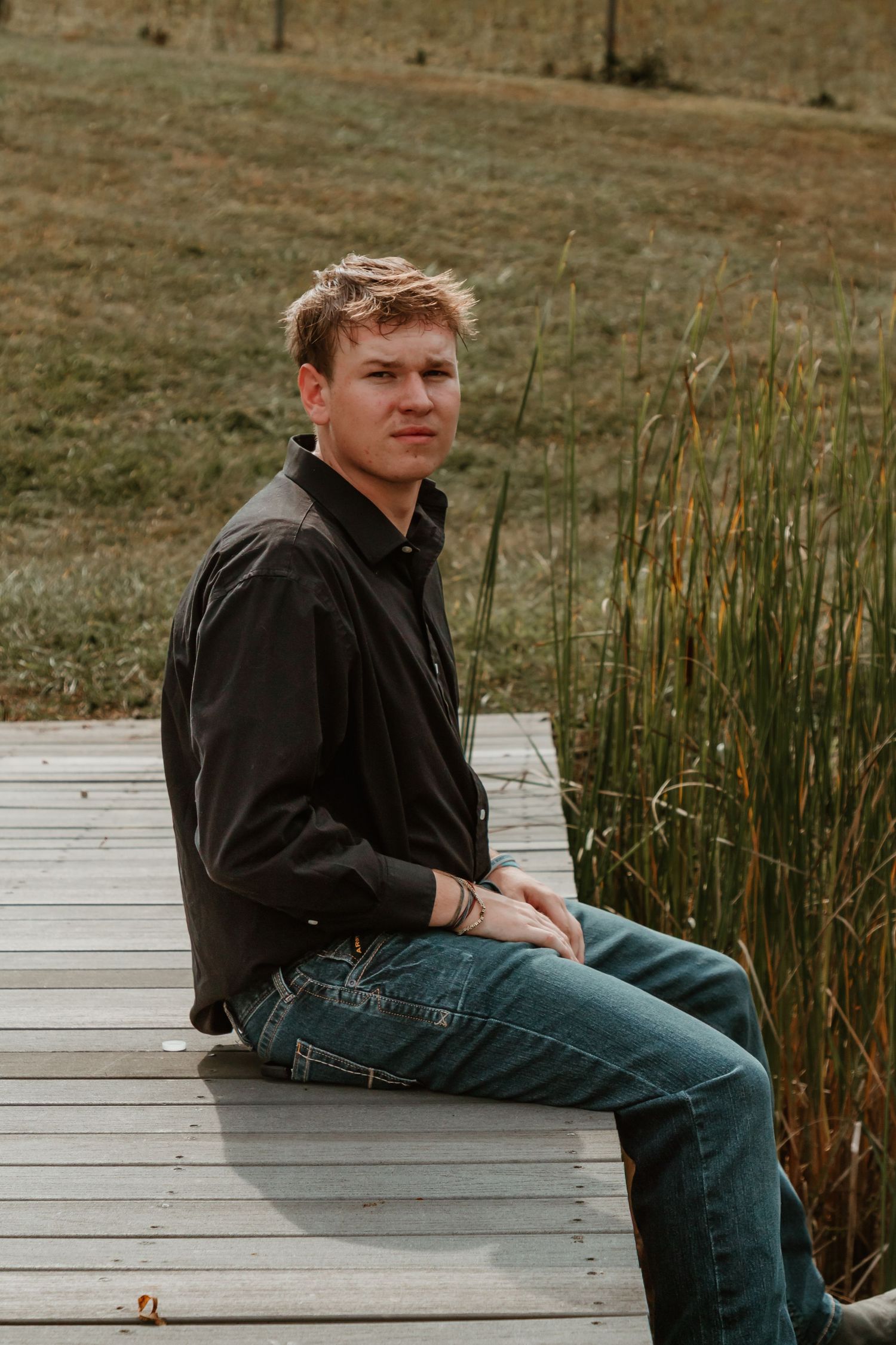 A series of photos showing someone in a dark jacket and jeans sitting casually on a wooden boardwalk near tall reeds.