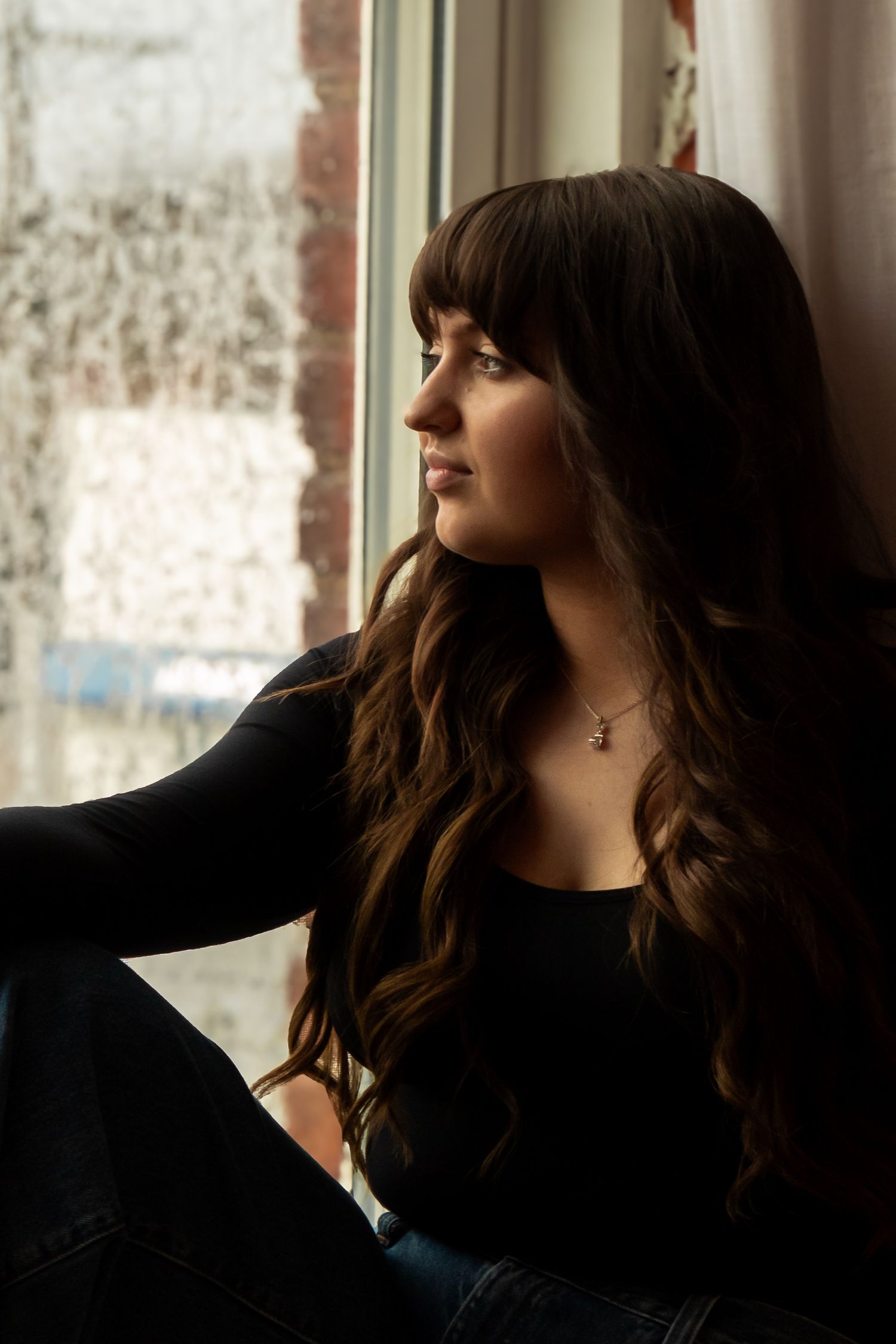 A woman with dark wavy hair gazes thoughtfully to the side in a series of moody portrait shots.