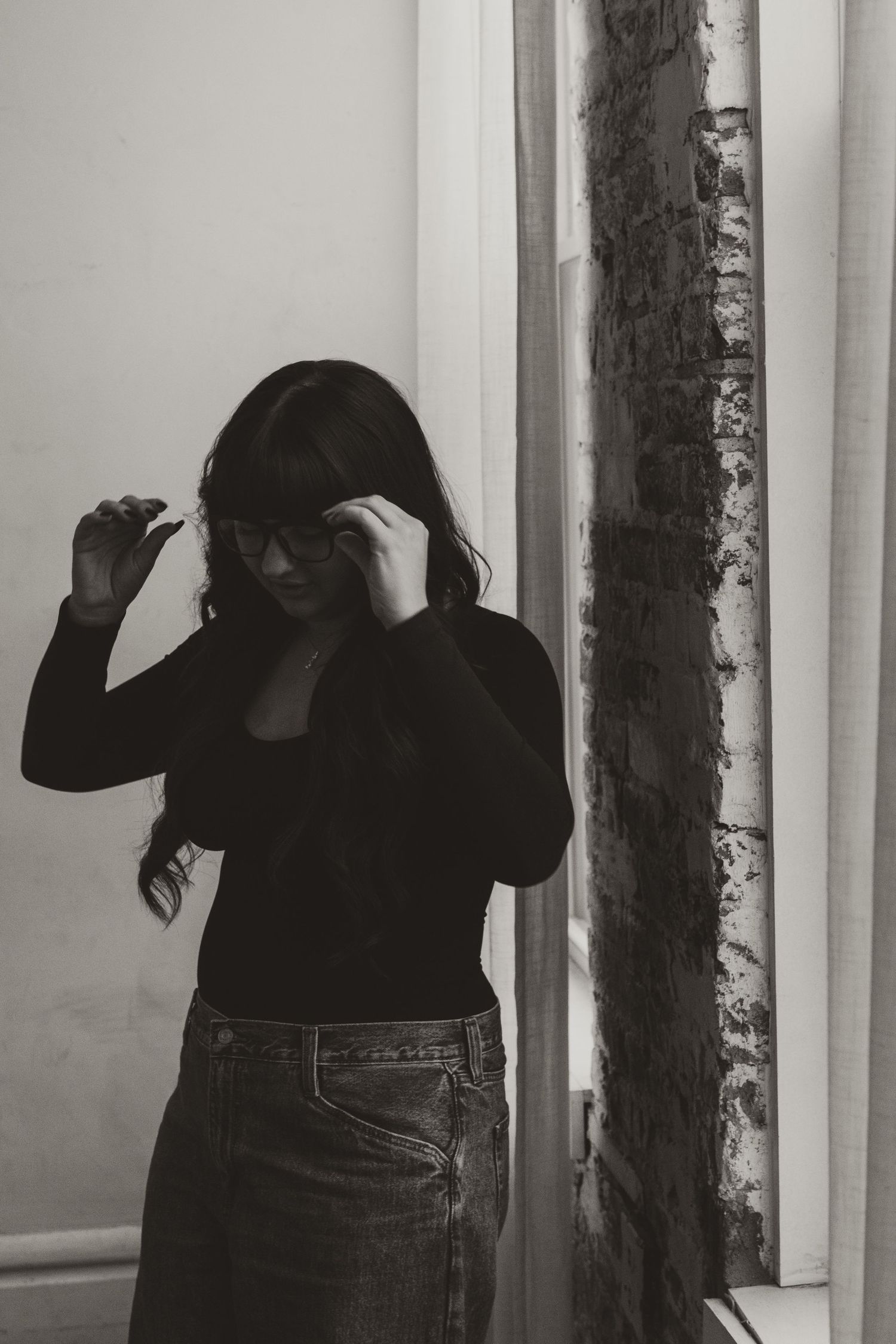 A series of black and white photos showing a figure in dark clothing posing between white columns.