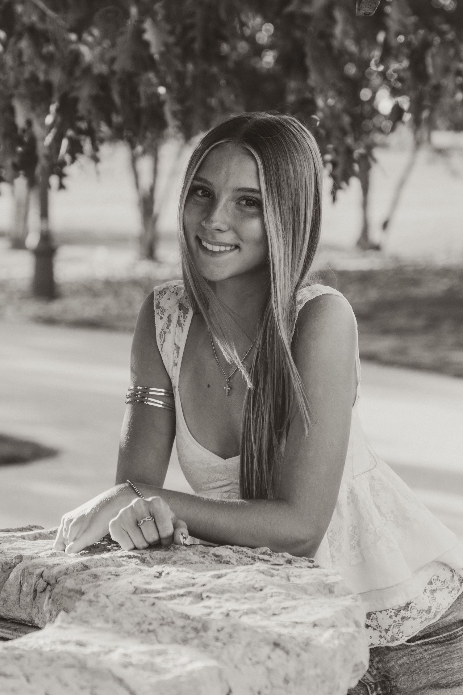 A collection of black and white portraits showing someone resting on a stone wall outdoors.