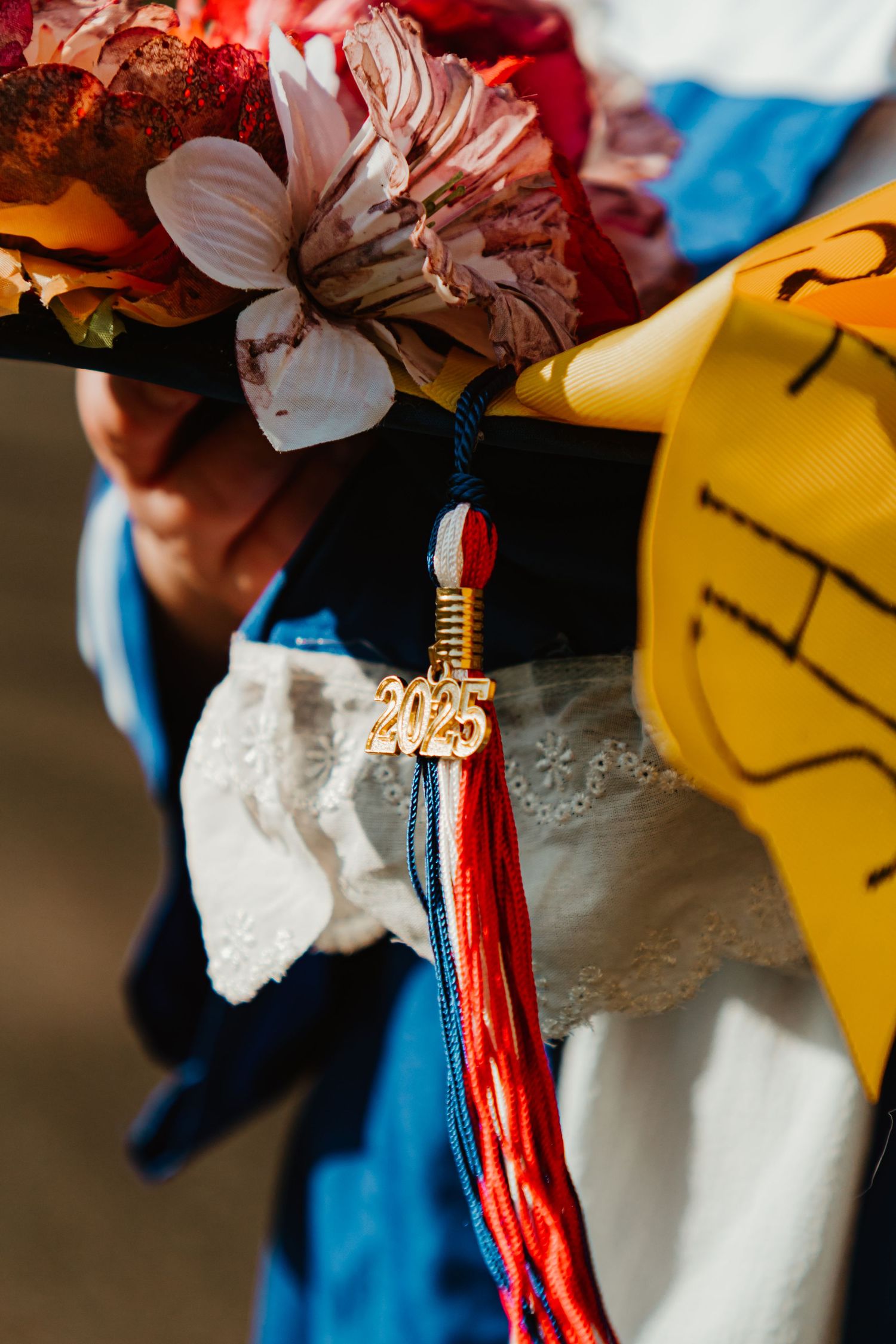 Close-up detail of red and white tassels hanging from a decorative ornament against a yellow background.