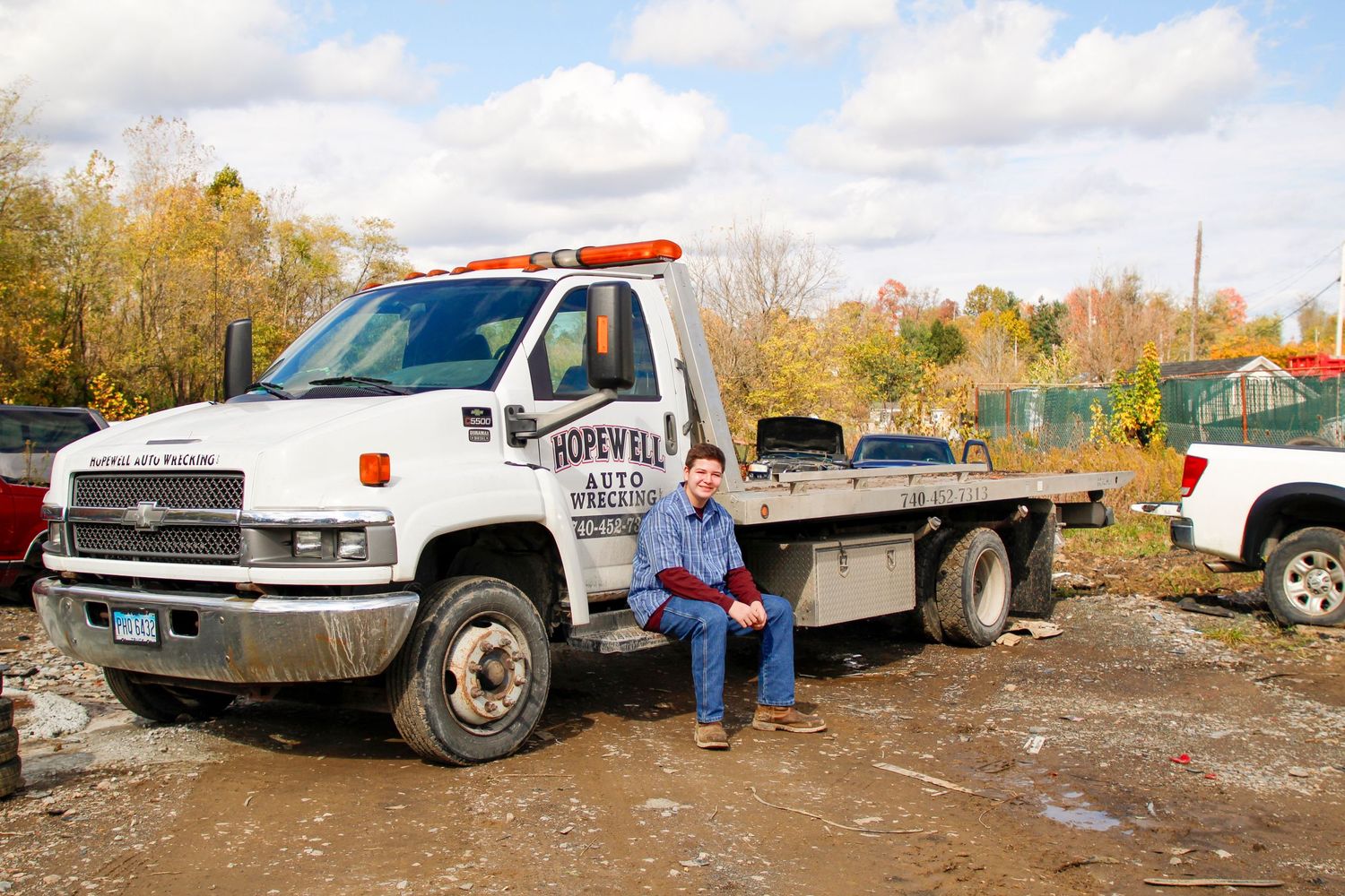 Person sitting on tow truck in industrial setting.