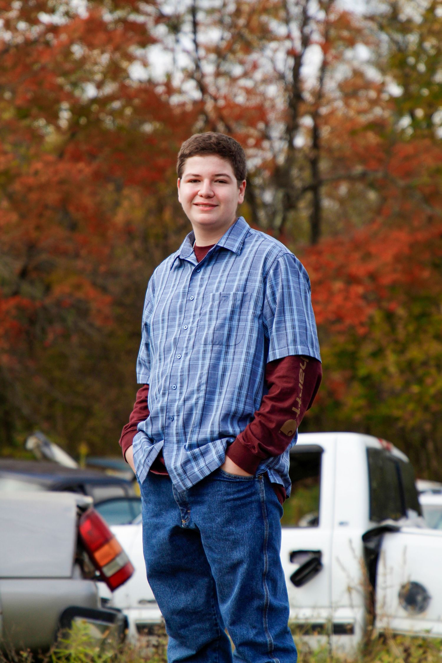 Casual outdoor portrait with autumn foliage in background.