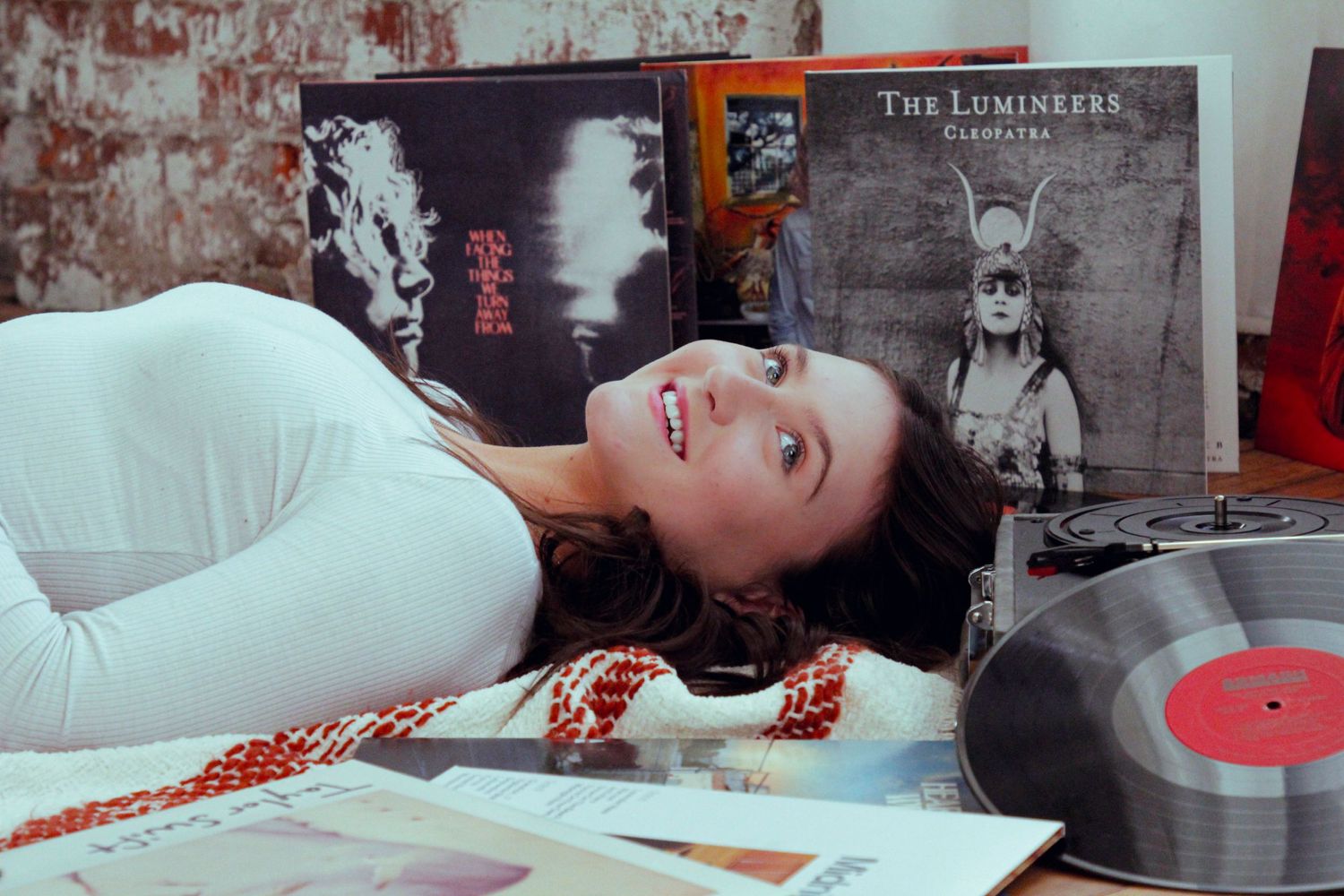 Relaxed pose with vinyl records and album covers in background.