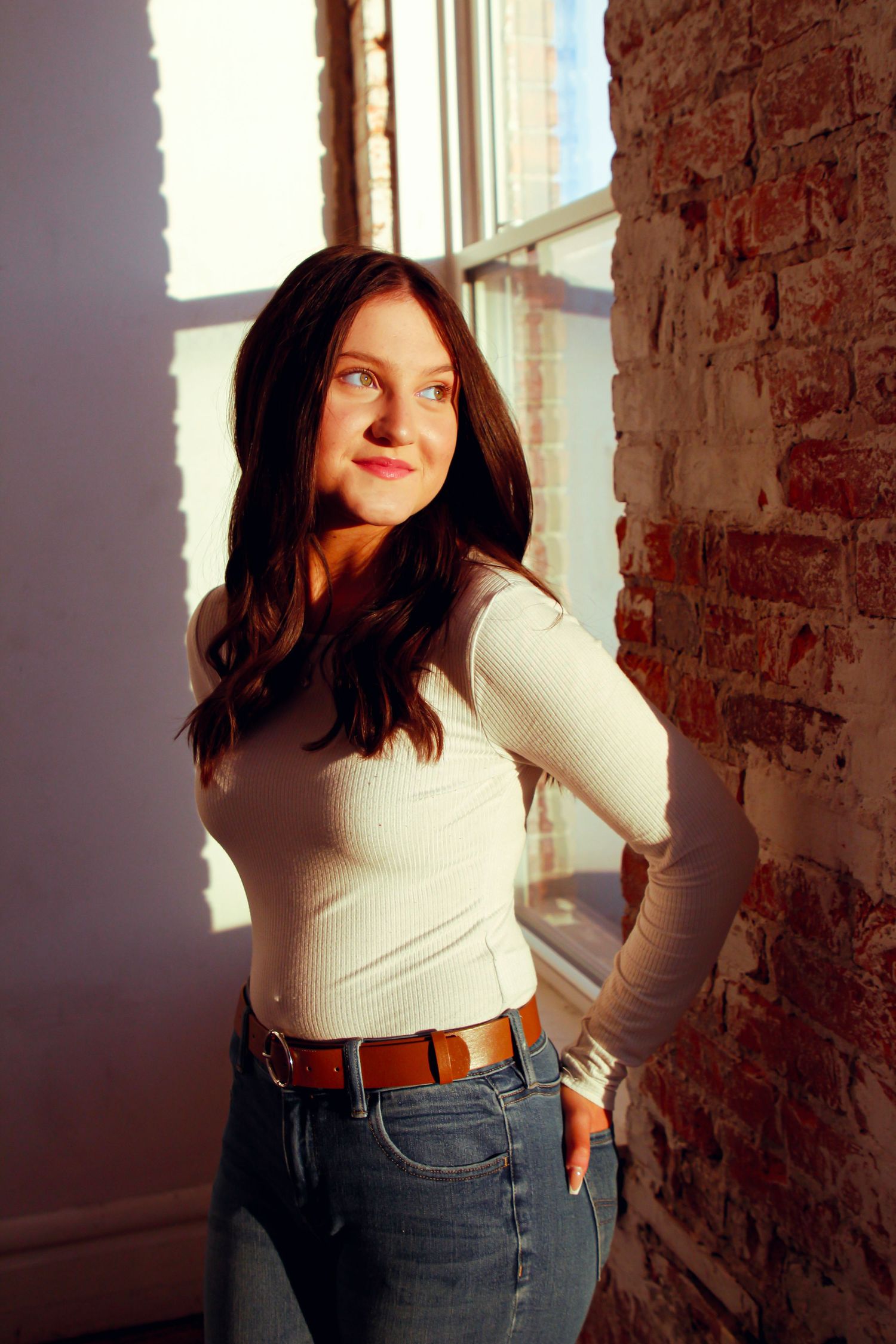 Portrait by brick wall with natural window lighting.