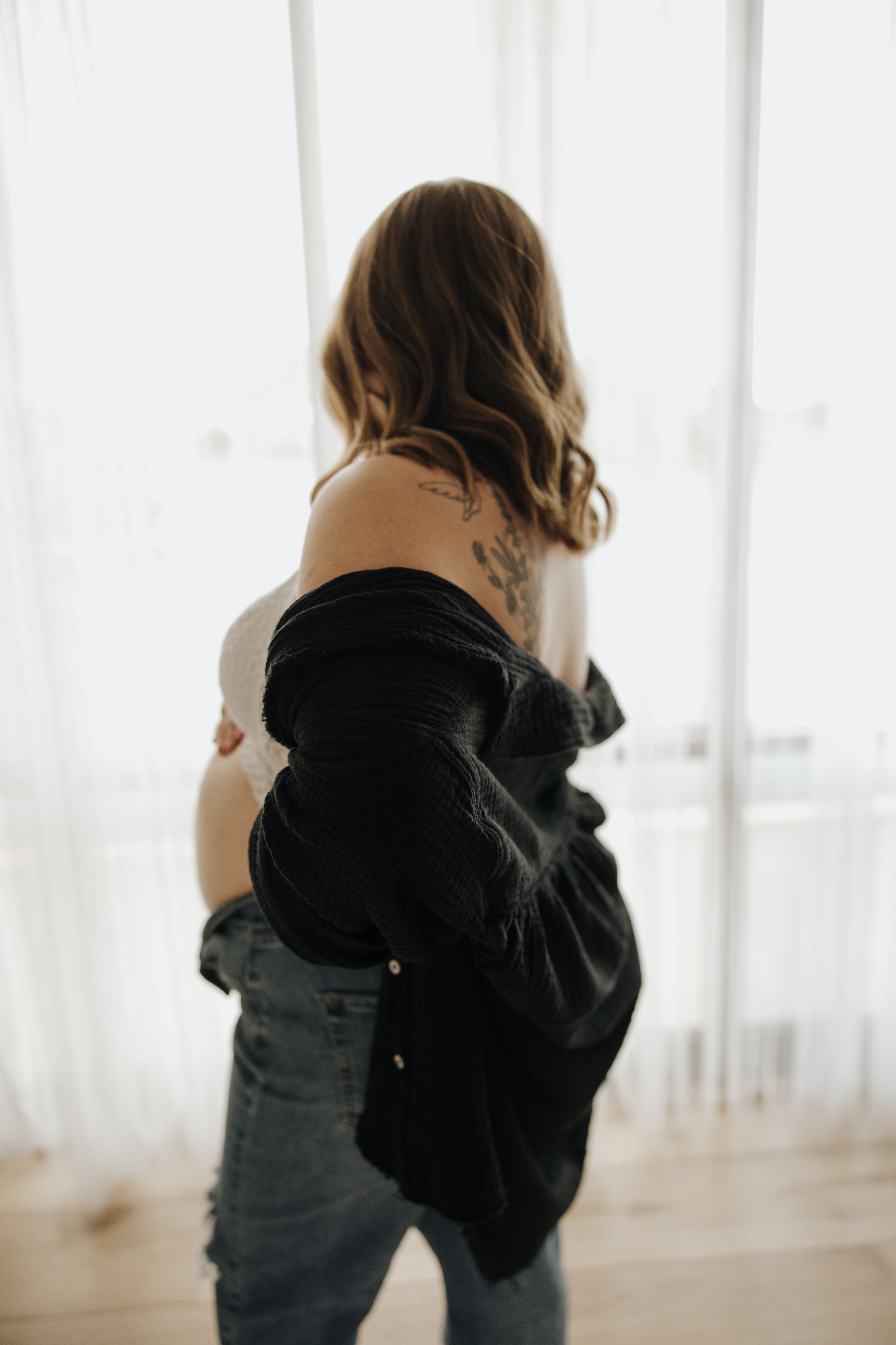 Artistic boudoir maternity photo showing silhouette against bright window.