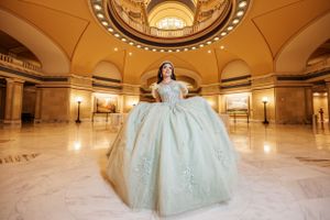 A mint green ball gown photographed in an ornate domed rotunda with marble floors.