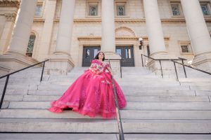 Dramatic pink ball gown photographed on grand white marble steps of a classical building.