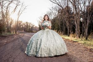 Elegant white ball gown photographed on a rustic path during golden hour sunset.