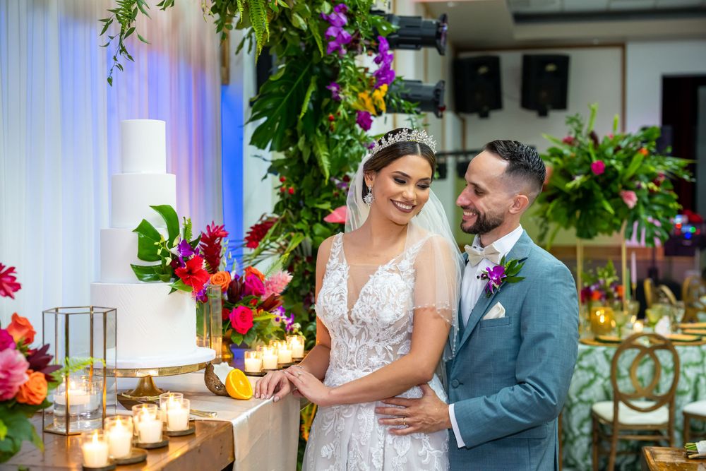 Newlyweds share intimate moment by candlelit display with tropical floral decor.