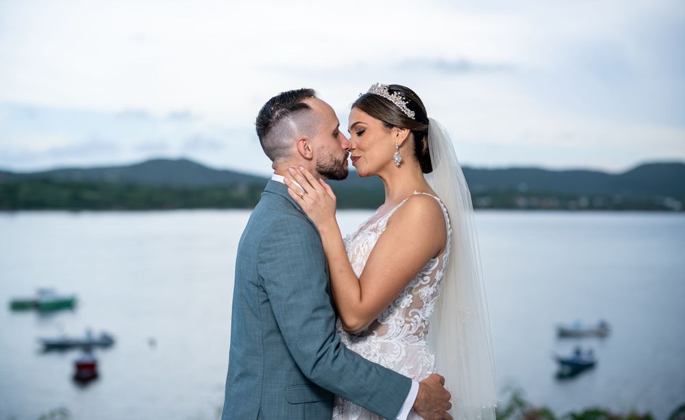 A romantic waterfront wedding portrait with a couple embracing against a scenic mountain lake backdrop.