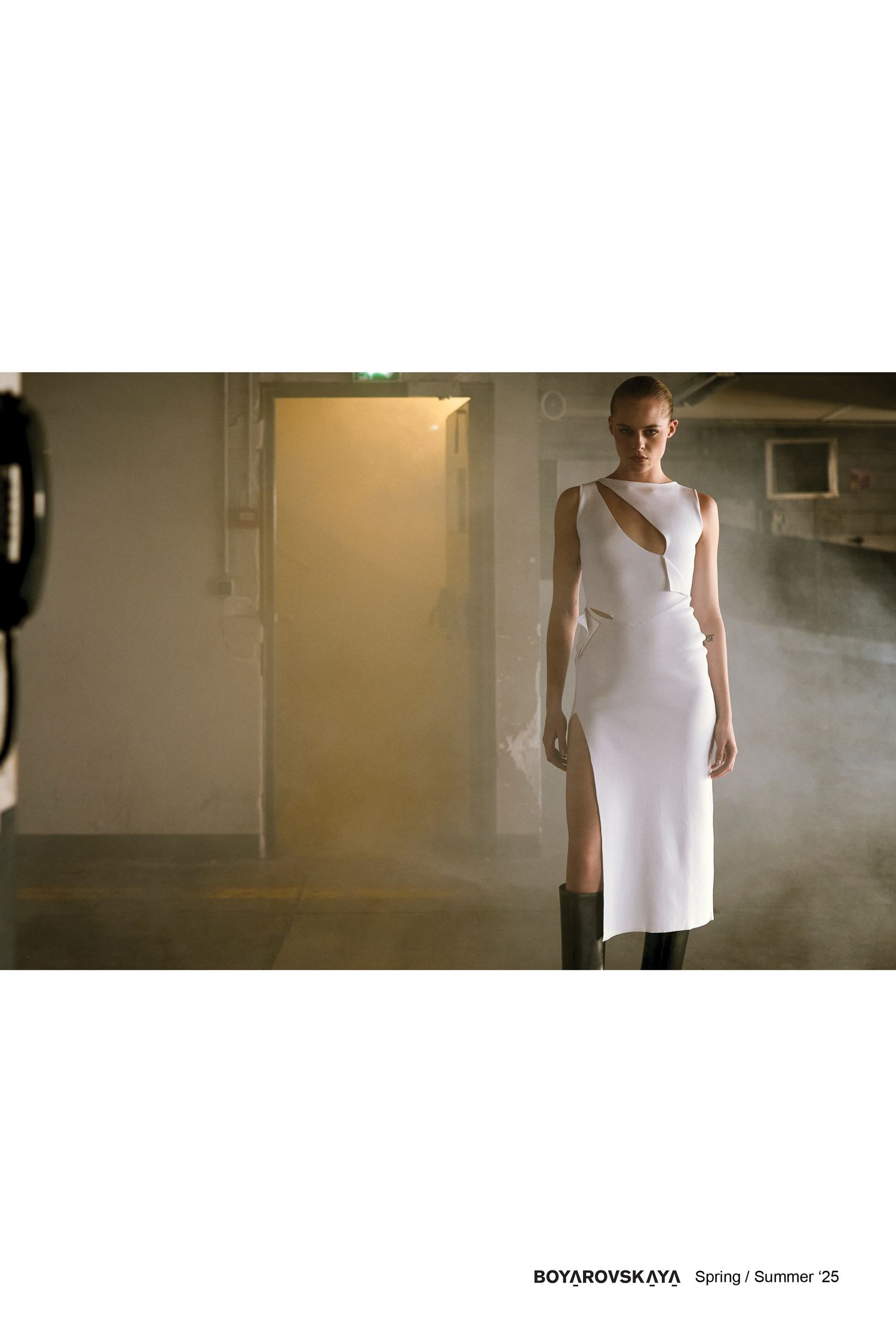 Le mannequin en robe blanche élégante pose dans un décor intérieur brumeux.