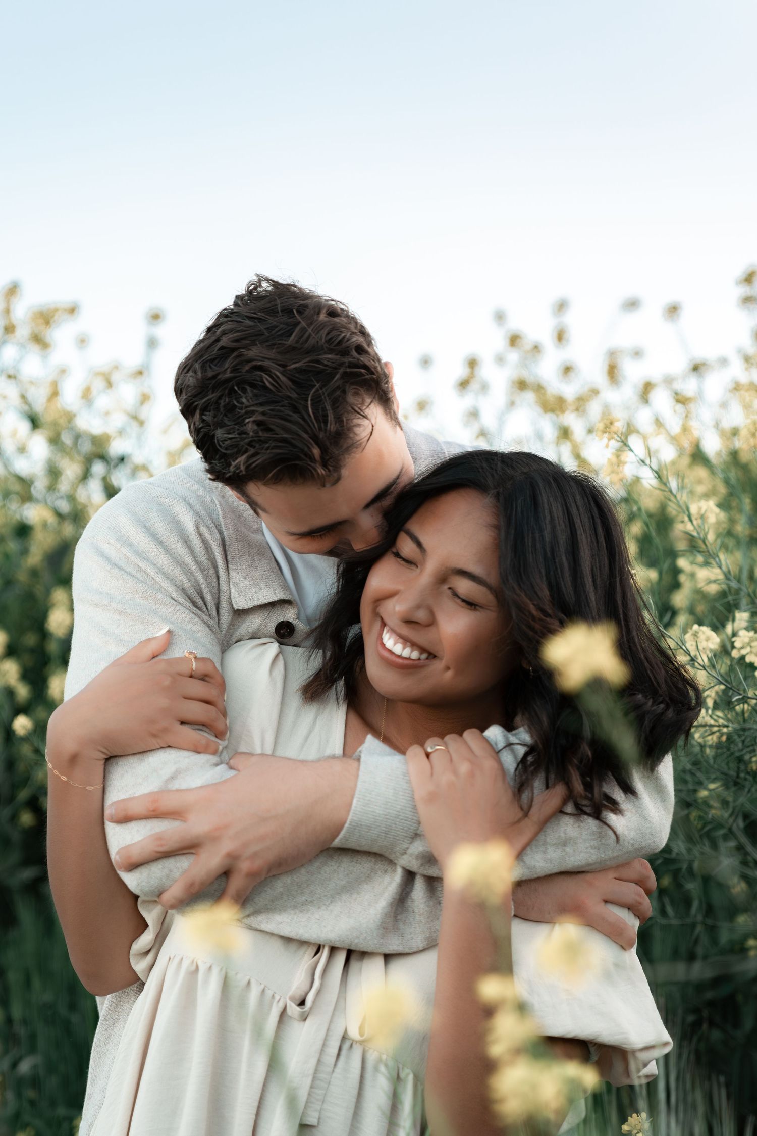Couple sharing intimate embraces and joyful laughter in an outdoor garden setting during golden hour.