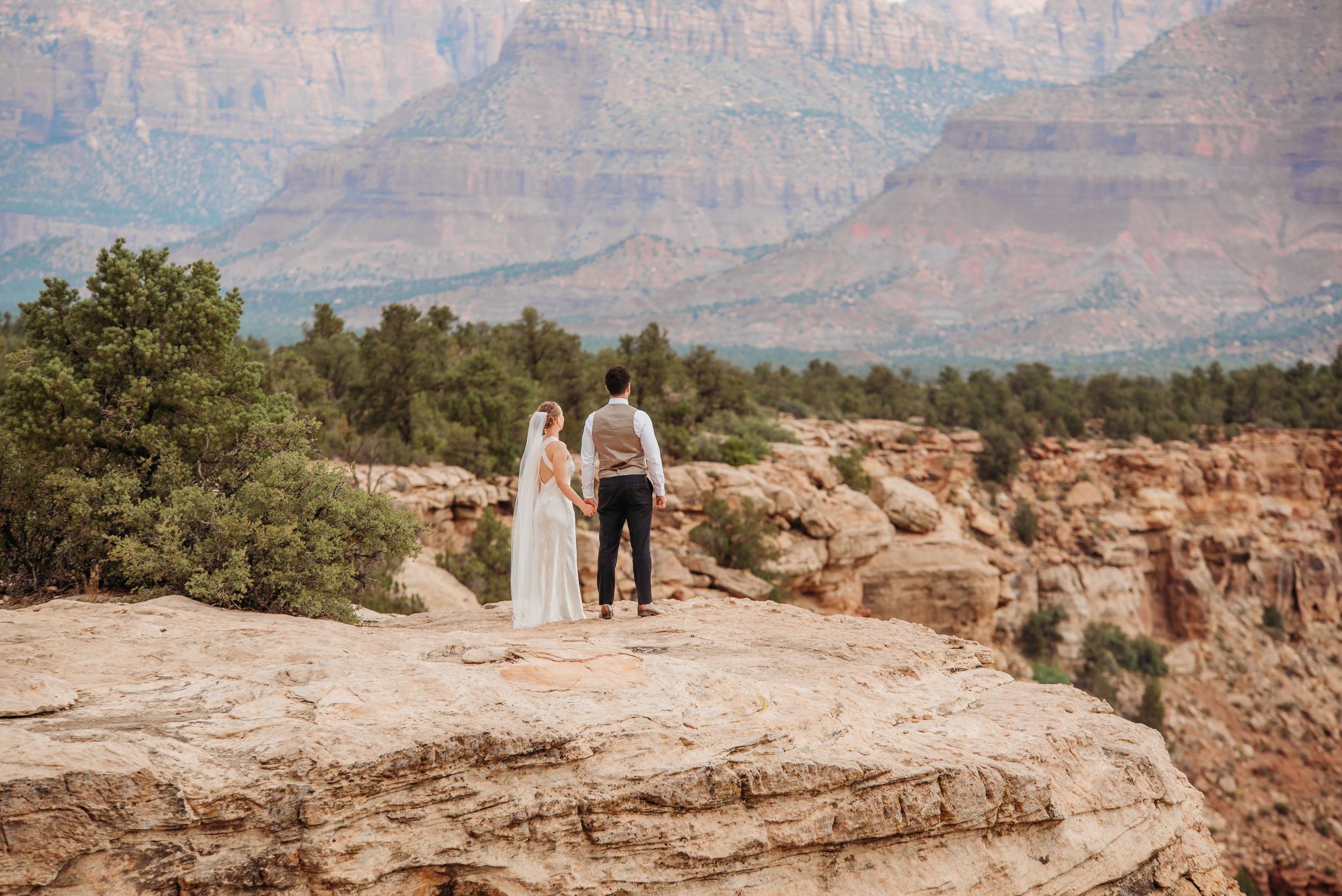 Bridal party in terracotta dresses posing against red rock canyon background.