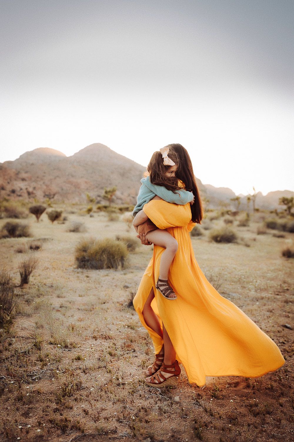 Joyful mom of eight in Joshua Tree National Park, holding her baby captured in a candid desert moment.