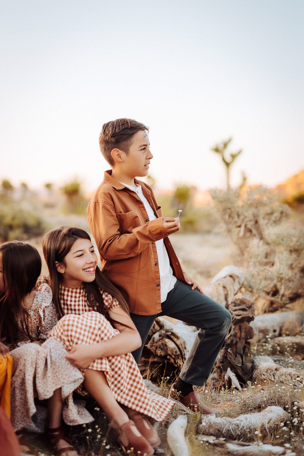 Group of siblings smiling and embracing in the Joshua Tree desert, with natural landscape in the background