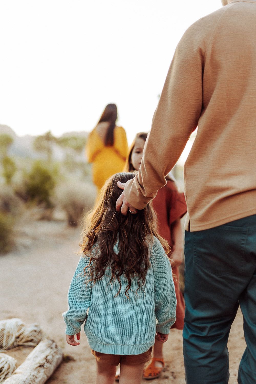 Happy family in earthy outfits, posing in a cadid way with the scenic Joshua Tree desert.