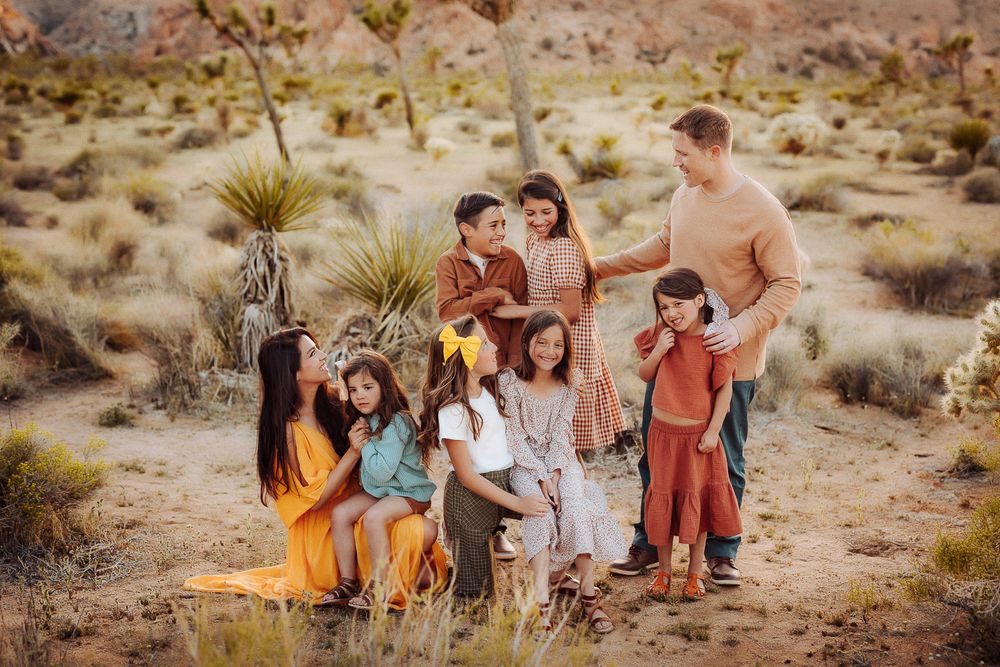 Warm and candid family portrait of eight in the Joshua Tree desert, captured at golden hour.