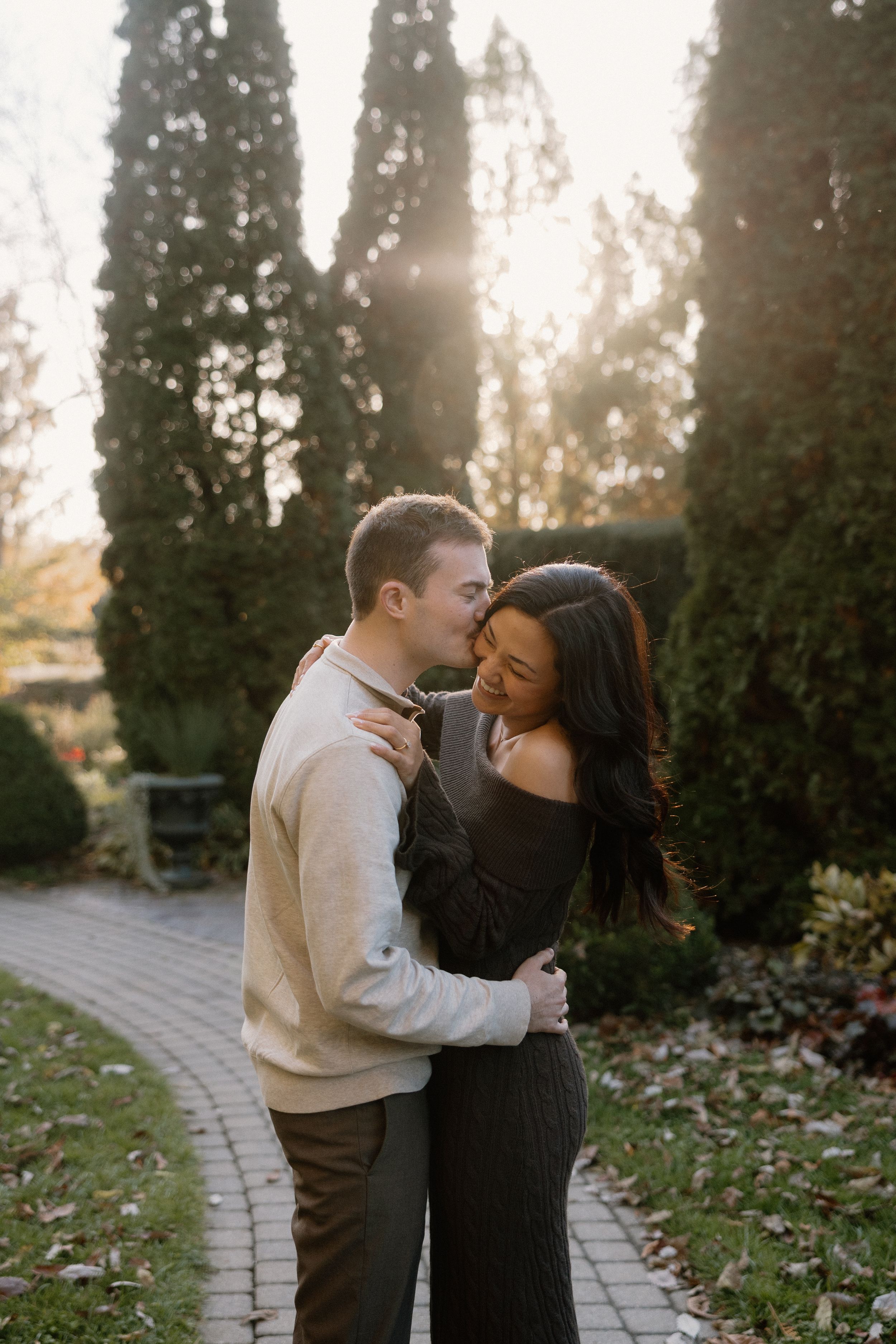 A romantic couple shares an intimate moment on a stone path surrounded by autumn leaves at golden hour.