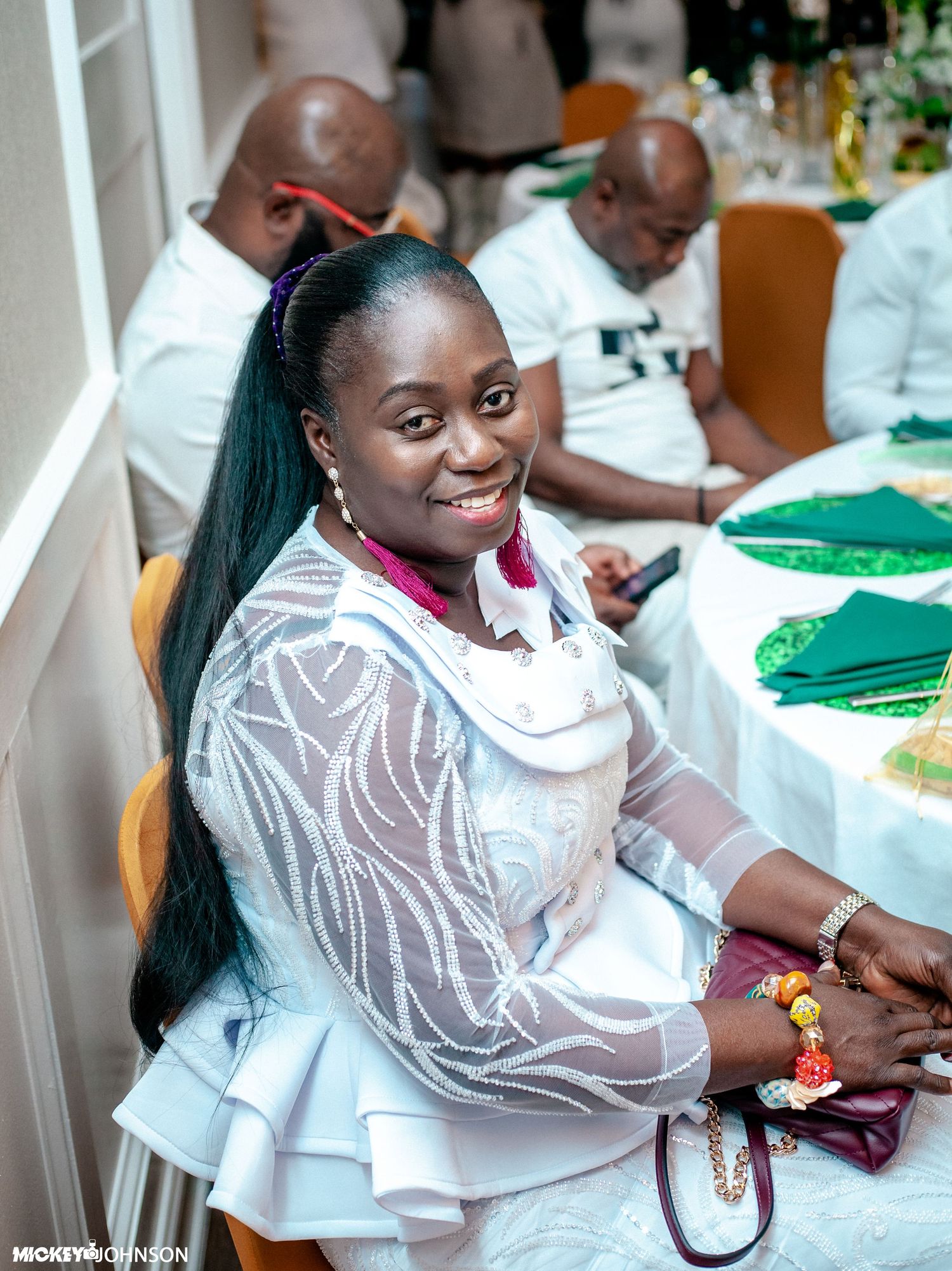 Person in white ruffled top smiling at formal event.