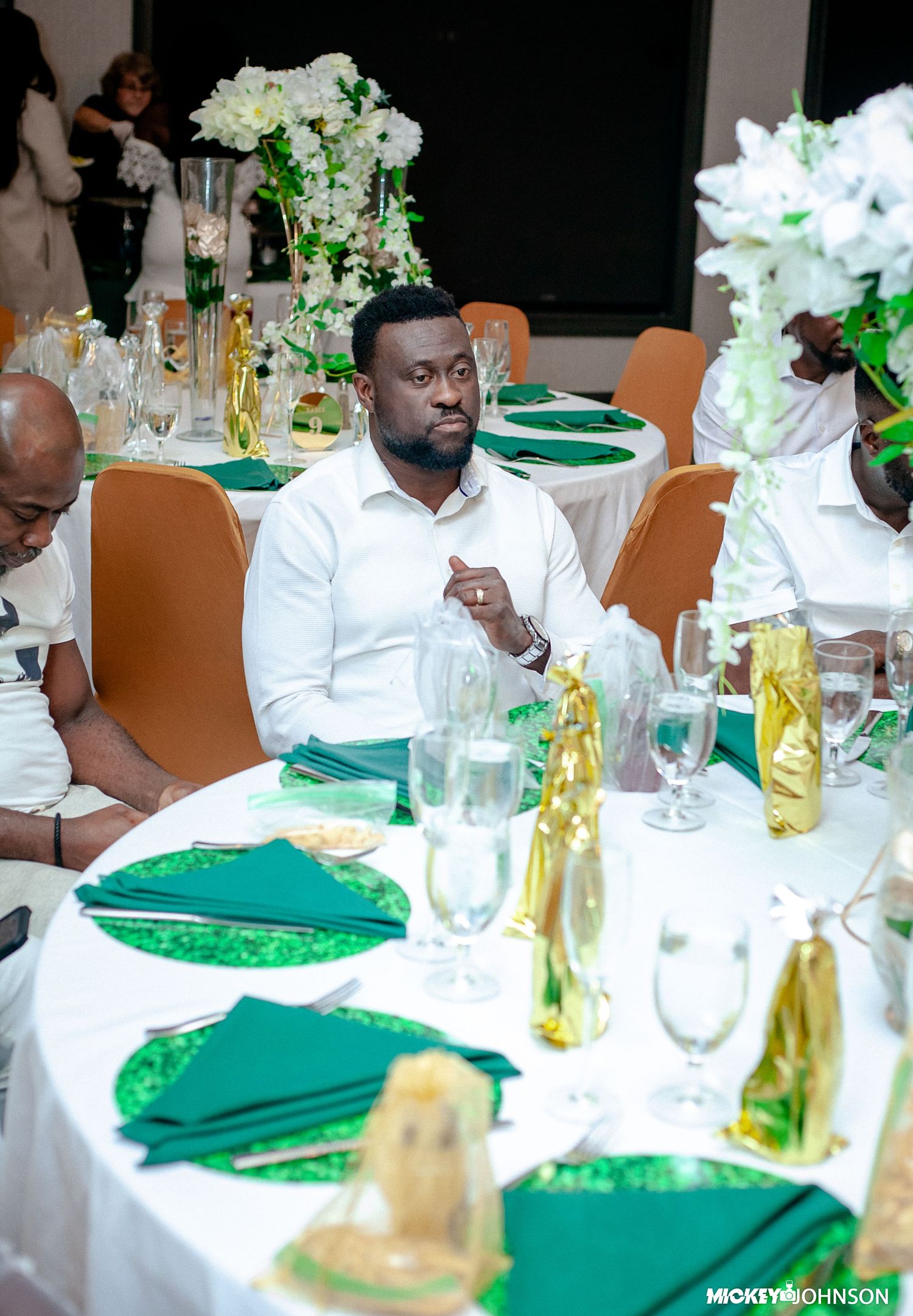 Elegant table setting with green napkins and white floral centerpieces.