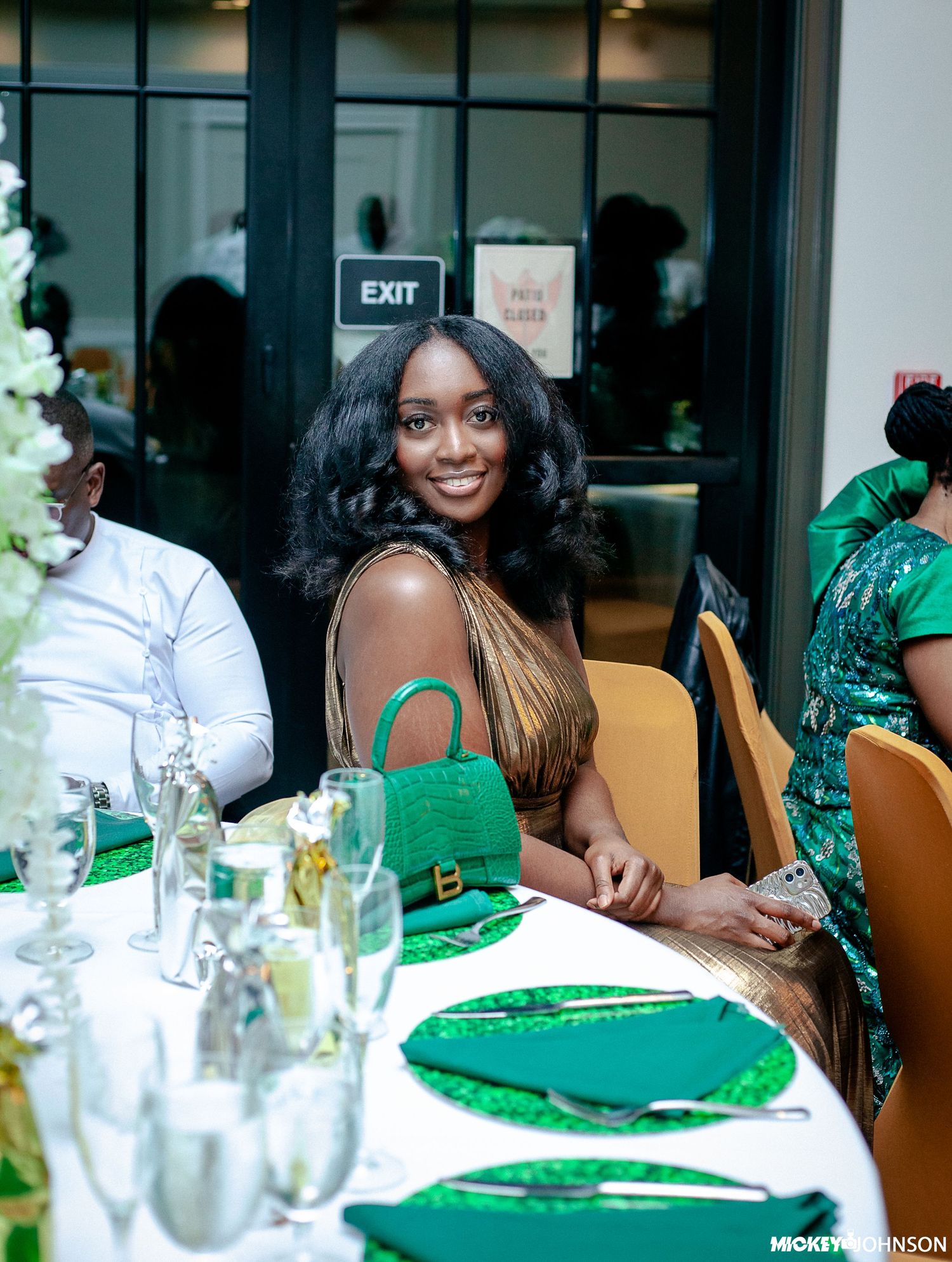Festive dinner party setting with green and gold decor on elegant table.