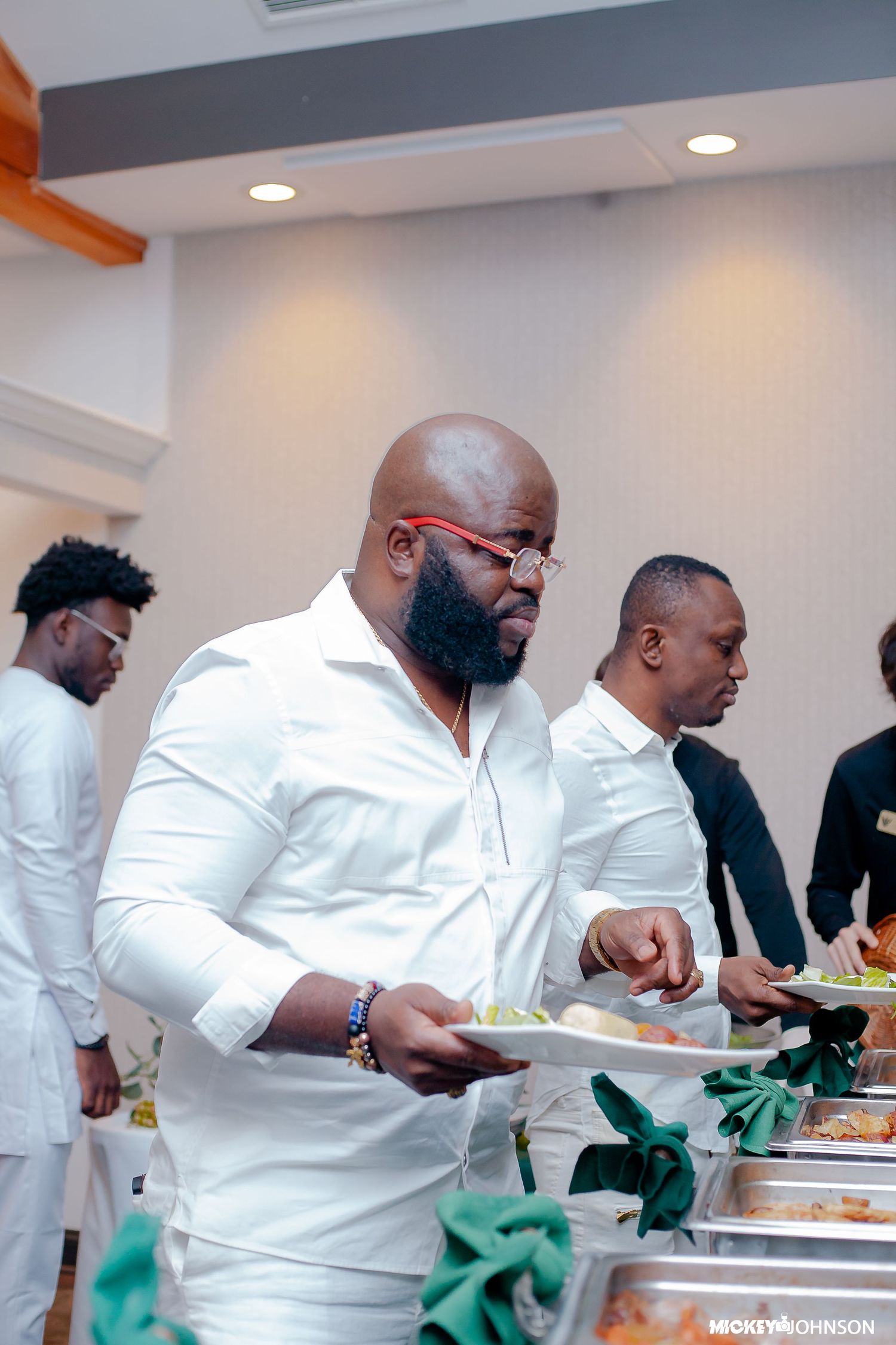 People in white attire serving themselves at buffet line.
