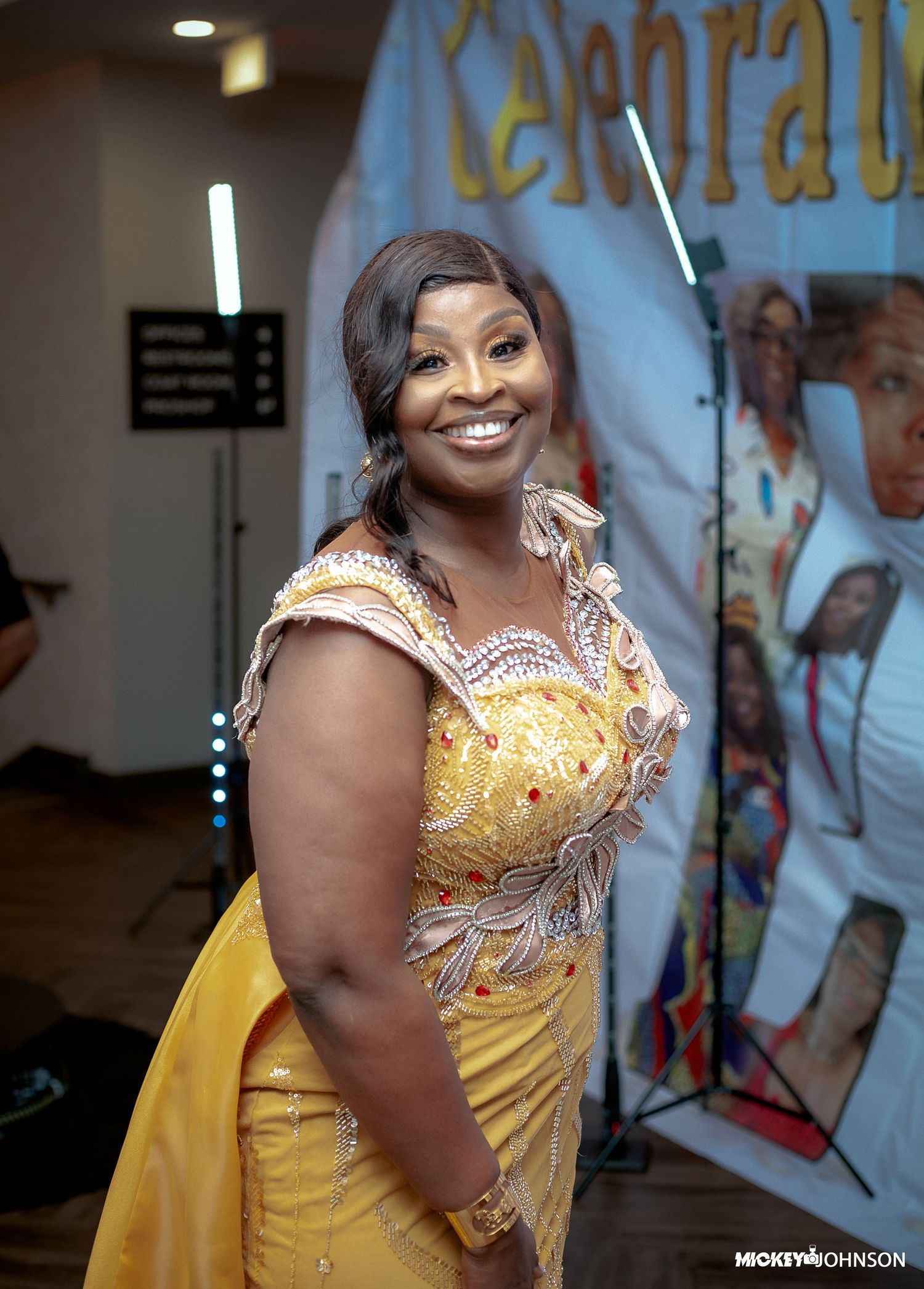 Woman in a sparkling yellow gown posing at a celebration.