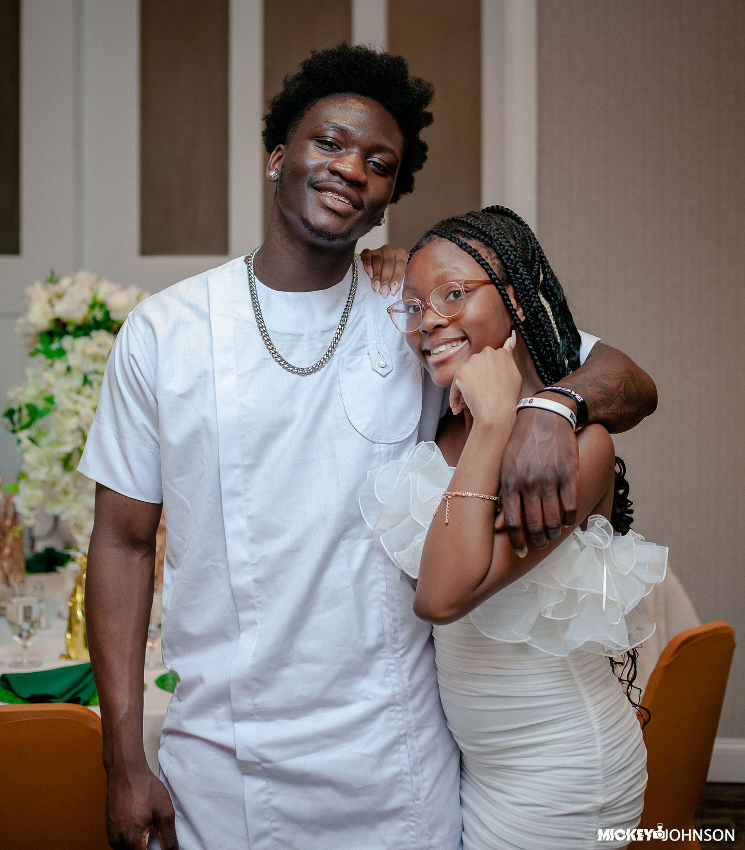 Guests in white outfits sharing a moment at formal event.