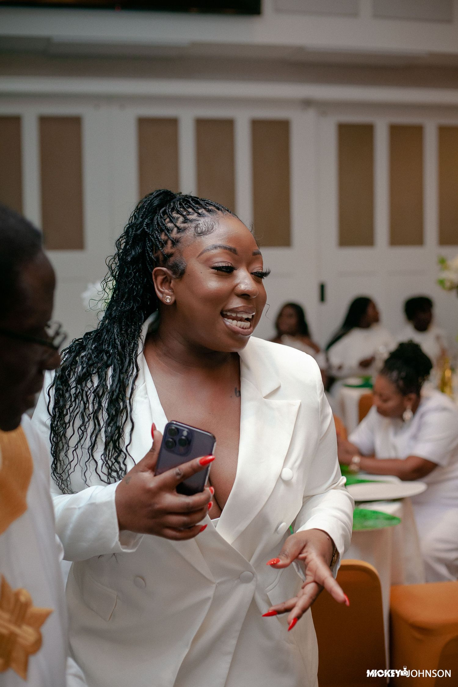 Guest in white blazer enjoying a moment at formal celebration.