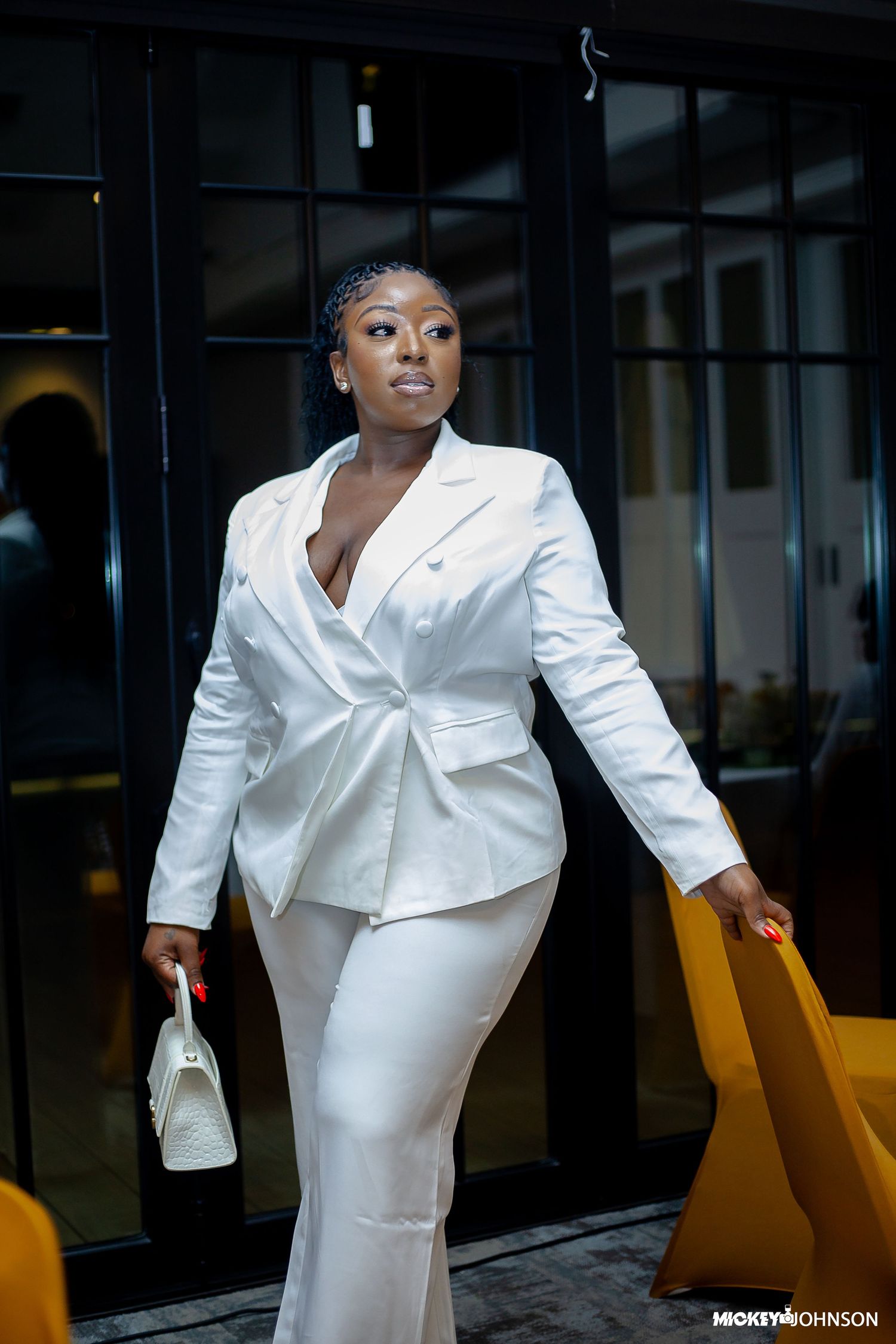 Elegant white pantsuit ensemble paired with a small handbag in a modern setting.