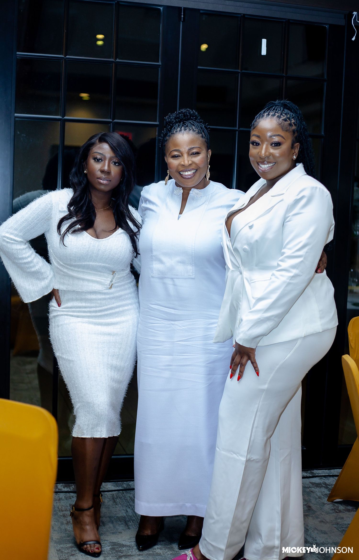 Group photo of attendees in white dresses and formal wear at an indoor celebration.