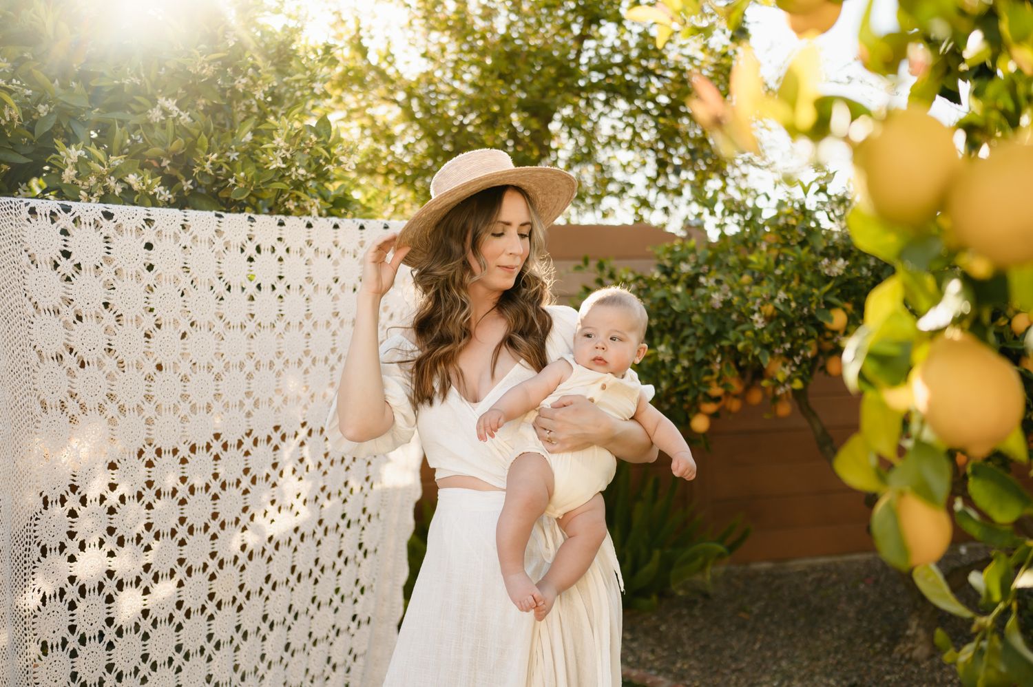mommy and me photoshoot Ventura in Citrus grove by Ventura family photographer, of mom in white dress holding baby