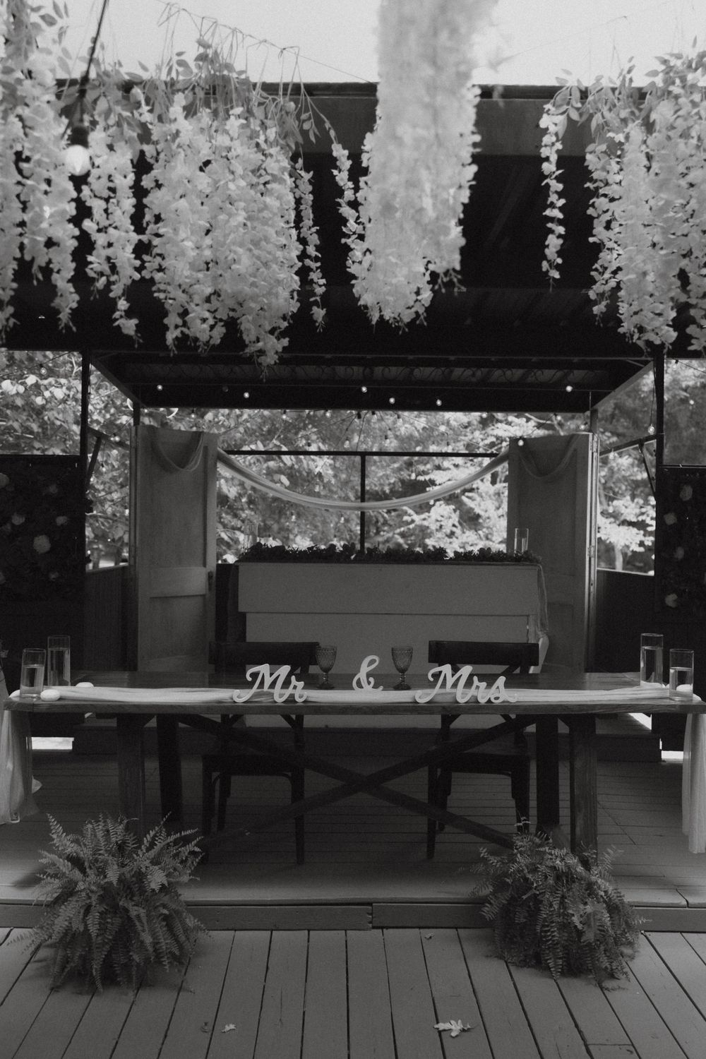 Black and white photo of wedding sweetheart table with Mr and Mrs sign and floral ceiling.