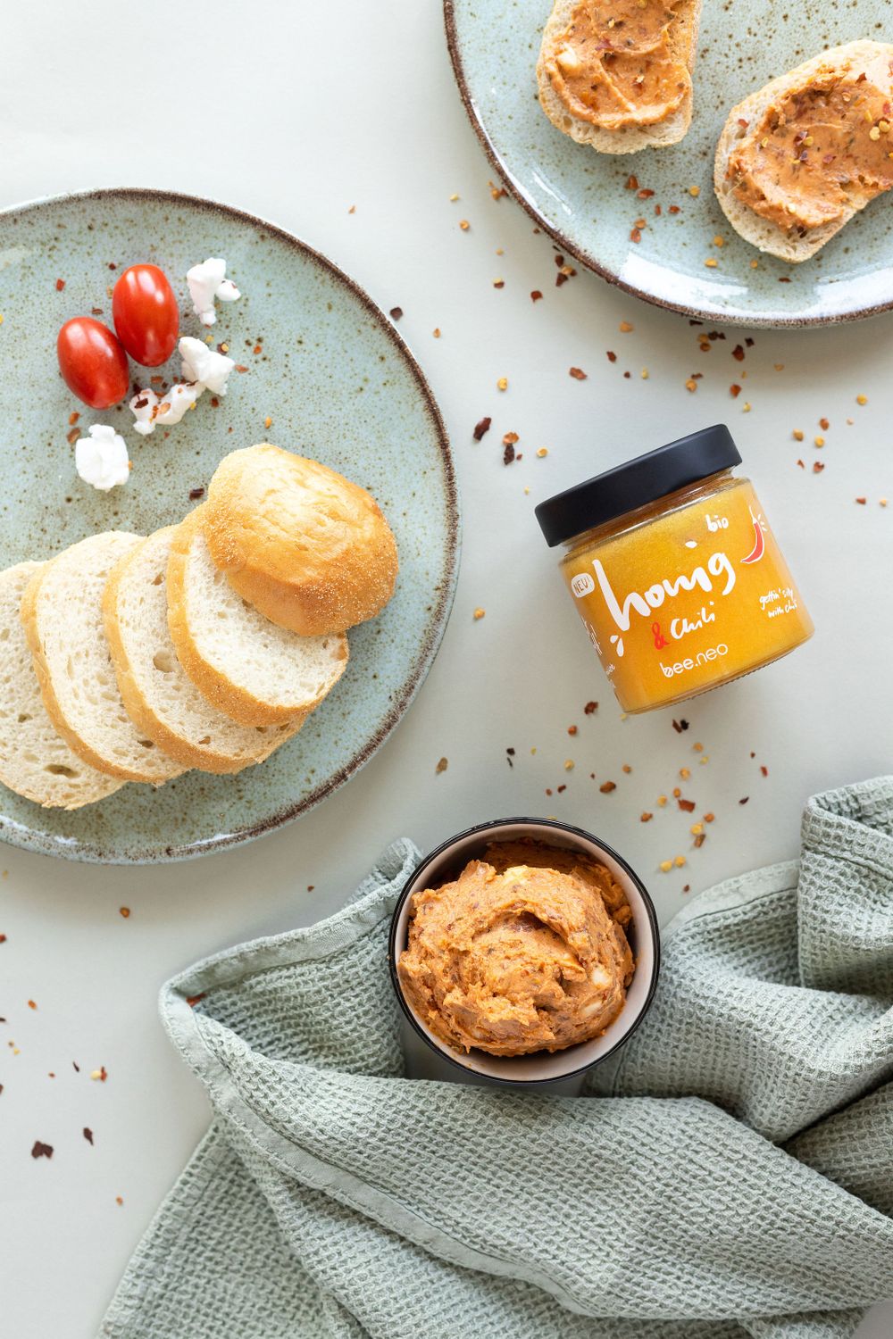 Flatlay of bread slices with honey jar and cherry tomatoes on ceramic plates.