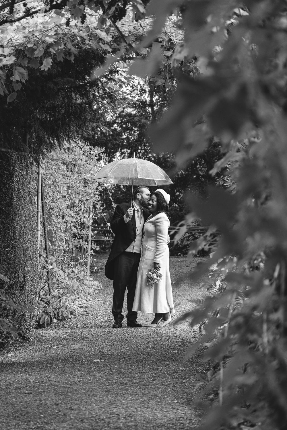 Newlywed couple stood under an umbrella for their creative shoot as it was raining in Schlosspark Andelfingen, Switzerland.