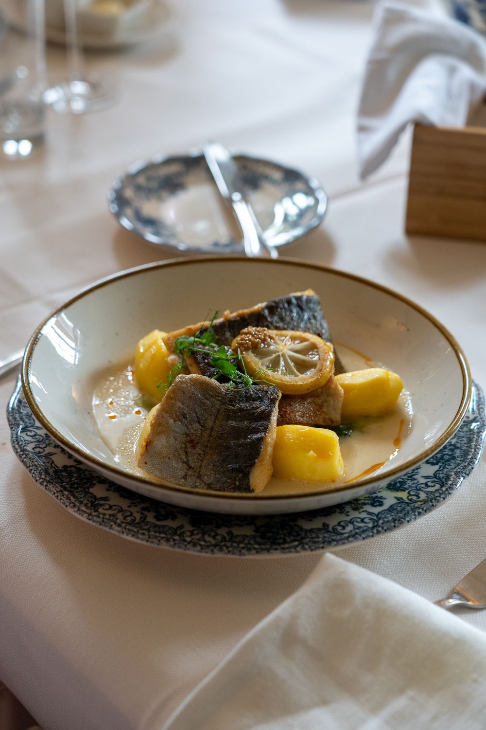 The main course of a wedding breakfast being served. The meal is fish with potatoes and sauce.