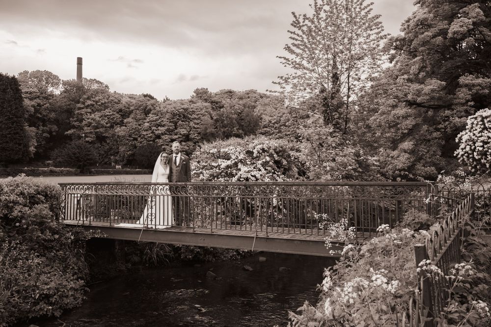 Bride and Groom stood on an iron bridge over the river in Bollington, Cheshire during their couples photoshoot on their wedding day.