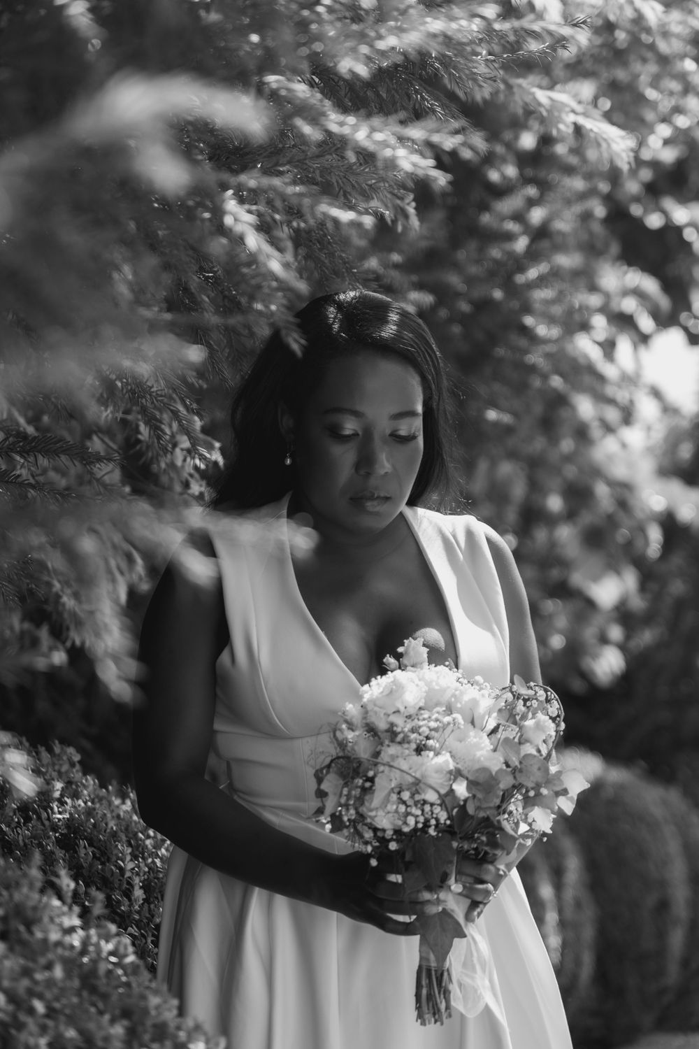 A black and white photograph of a bride who has just got married. She is looking down in deep thought at her bouquet of flowers.