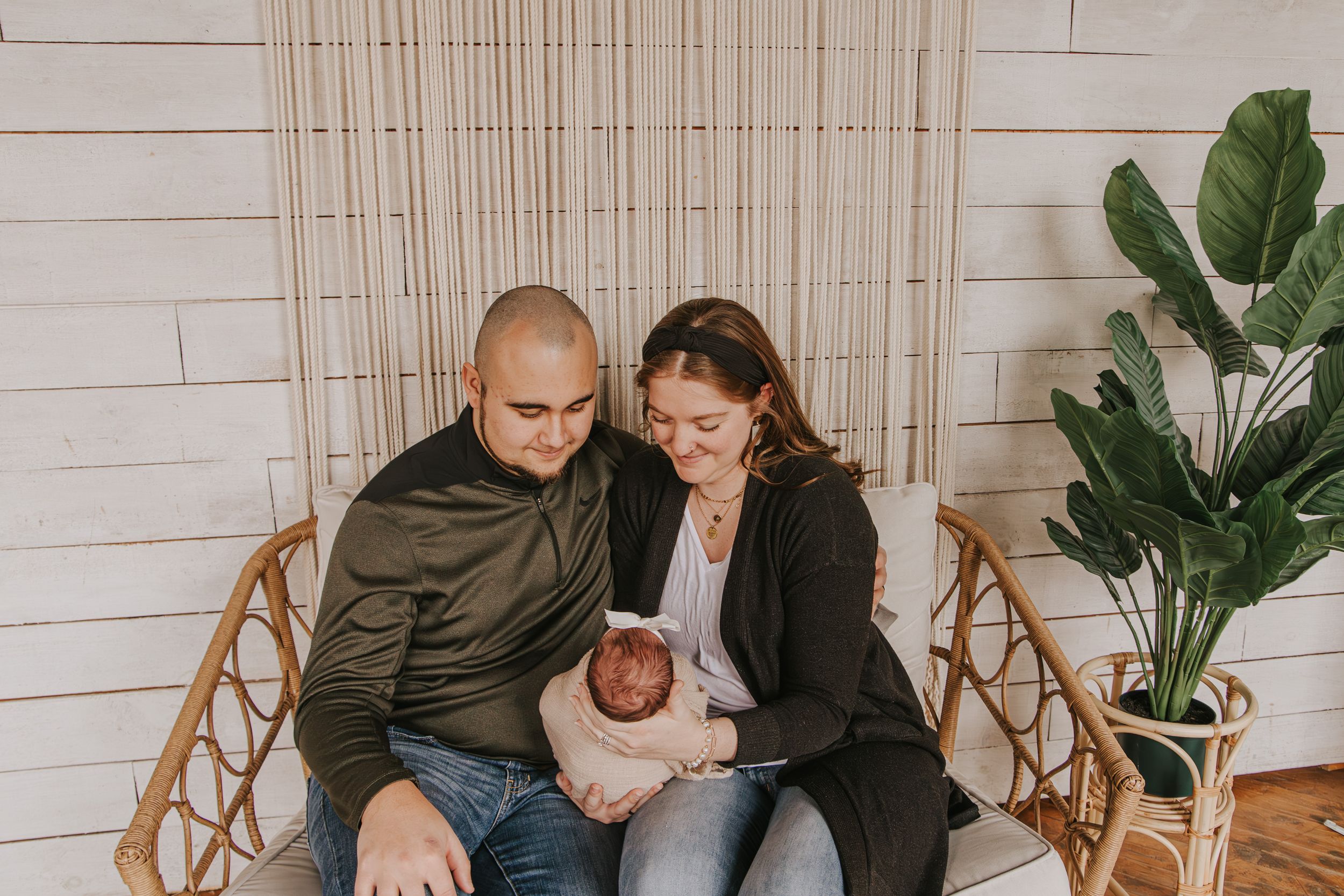 Family portrait session in bright room with wooden chairs and houseplants.