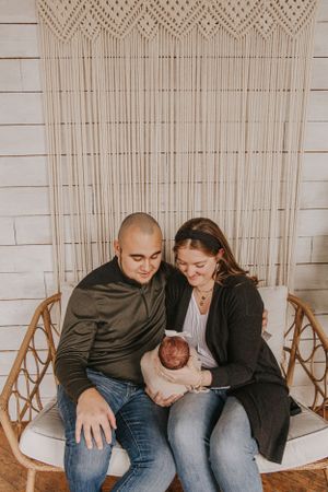 Family sharing tender moment while sitting on white couch against neutral wall with hanging decor.