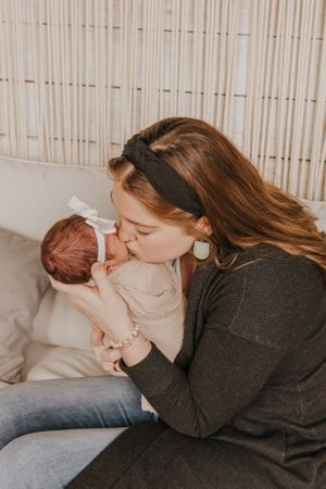 Intimate family moment captured on white couch with beige curtained background.
