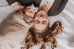 Artistic overhead portrait shot on white bedding with natural lighting.