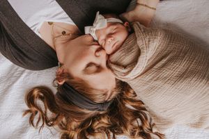 Intimate newborn photography session shows tender moments on white bedding.