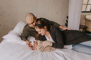 Family lifestyle scene on white couch against neutral wall with hanging decor.