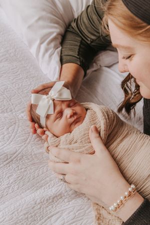 Close-up shots of parents cradling their swaddled newborn baby.